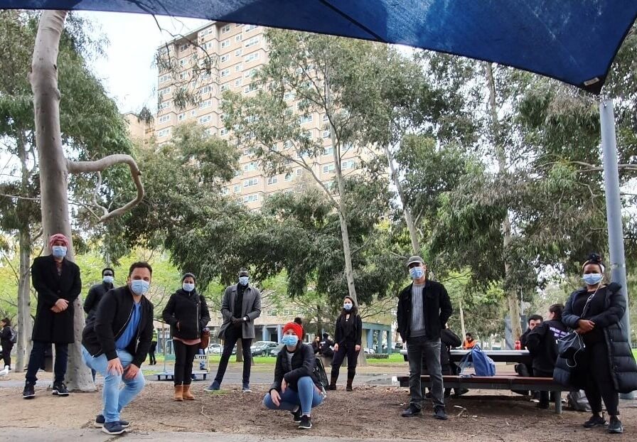 A group of bicultural BSL staff standing in front of a residential tower block wearing masks.