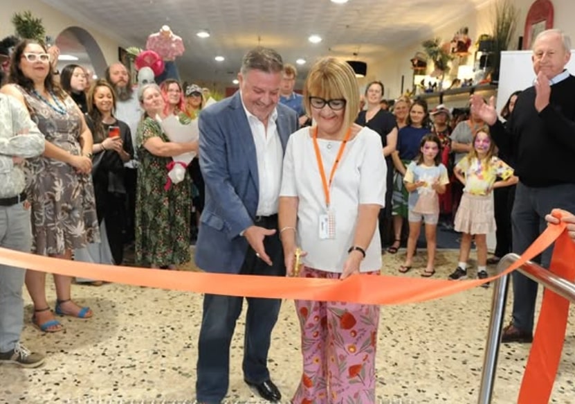 Joe Mirabella and an long-standing volunteer cutting the grand opening ribbon in front of a crowd. 